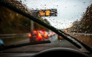 Pare-brise mouillé par forte pluie, essuie-glaces et feux flous