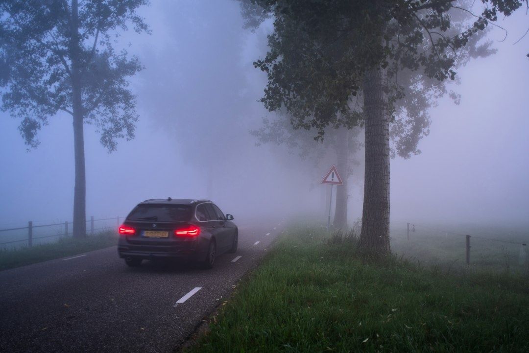 Voiture roulant prudemment sur une route plongée dans un épais brouillard